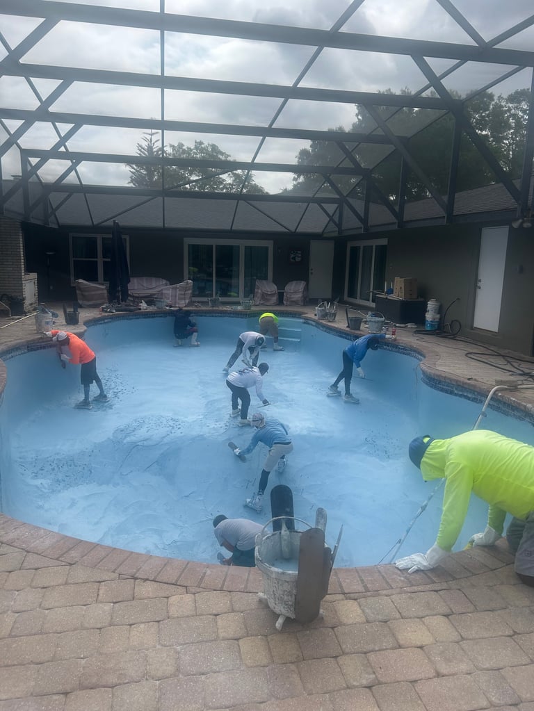 Workers in bright vests performing maintenance on an indoor swimming pool with blue water and glass ceiling structure